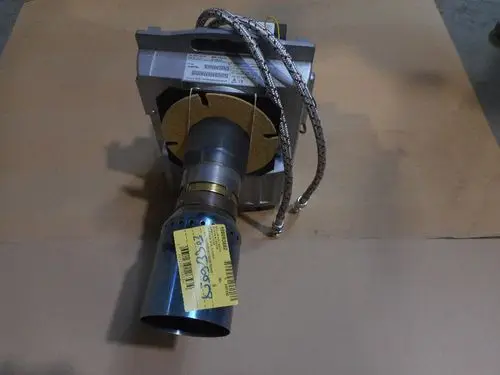 Ölbrenner von Remeha, sichtbar auf einem neutralen Untergrund, mit Metallanschlüssen und einem kurzen Auslassrohr. Einige technische Details sind auf einem Etikett angebracht.
